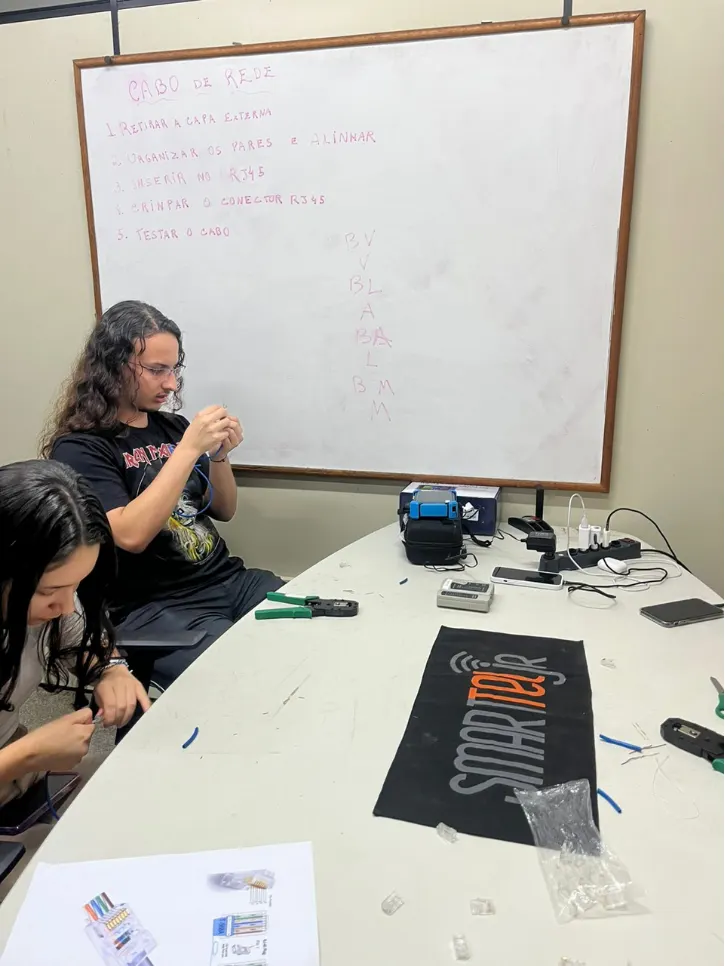 Capacitação da SmartTel Jr: membros aprendendo a crimpar conectores RJ45 em cabos de rede.