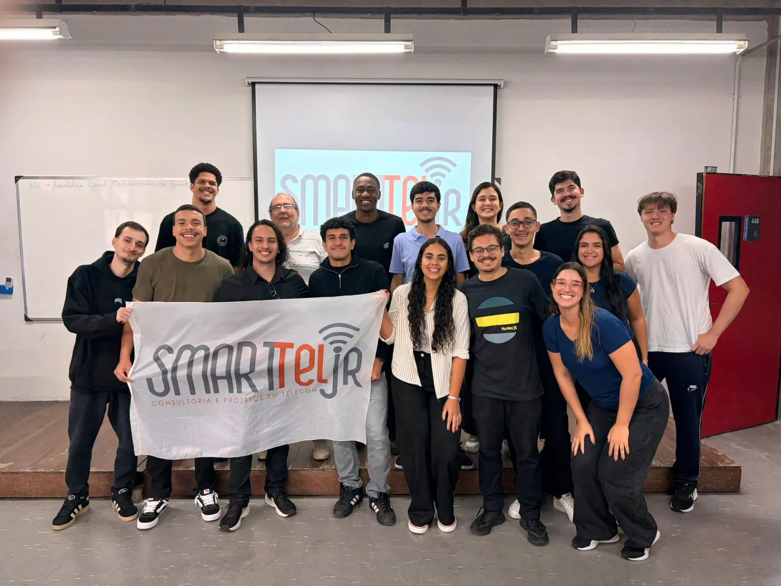 Equipe da SmartTel Jr reunida com a bandeira da empresa.
